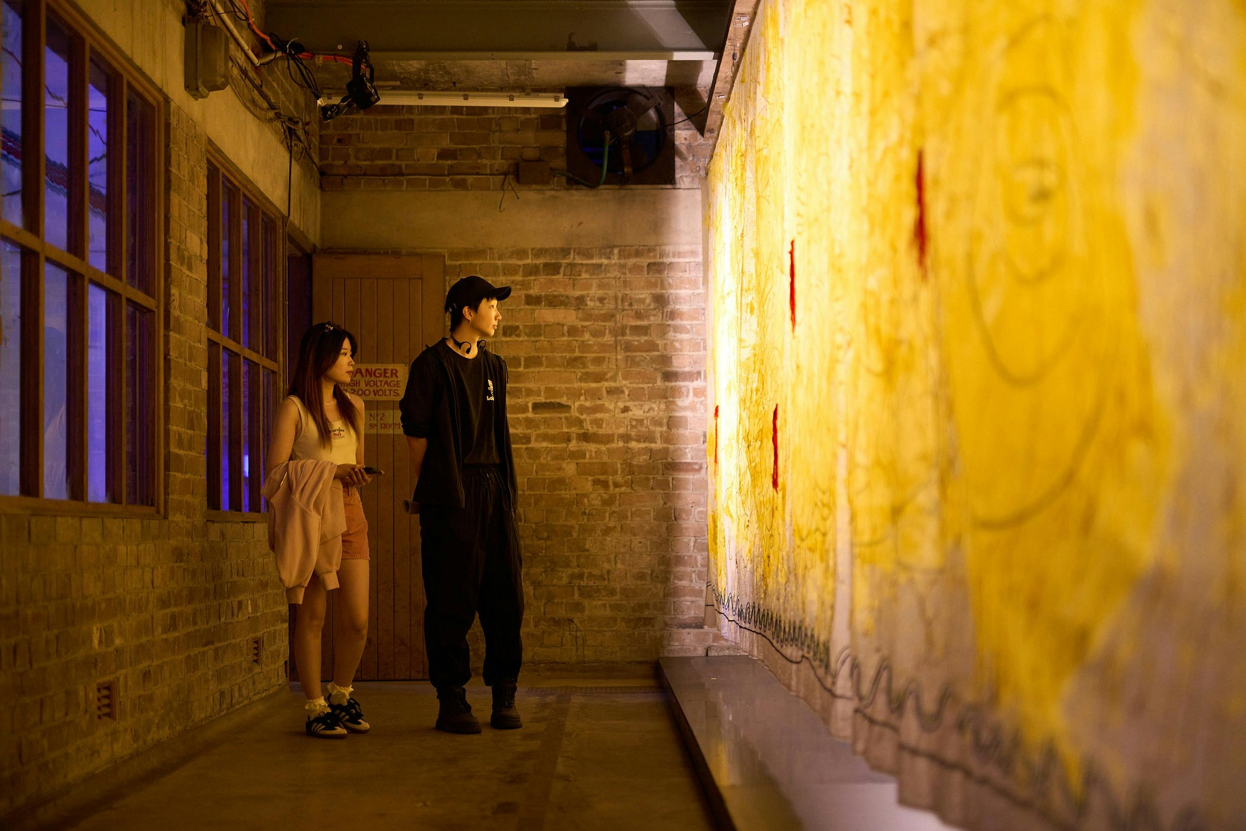 couple viewing illuminated textile artwork in remediated power station space