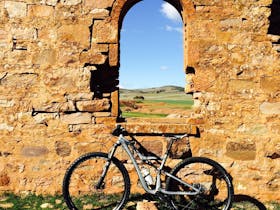 An old stone ruin with an arch window and a bike leaning against it