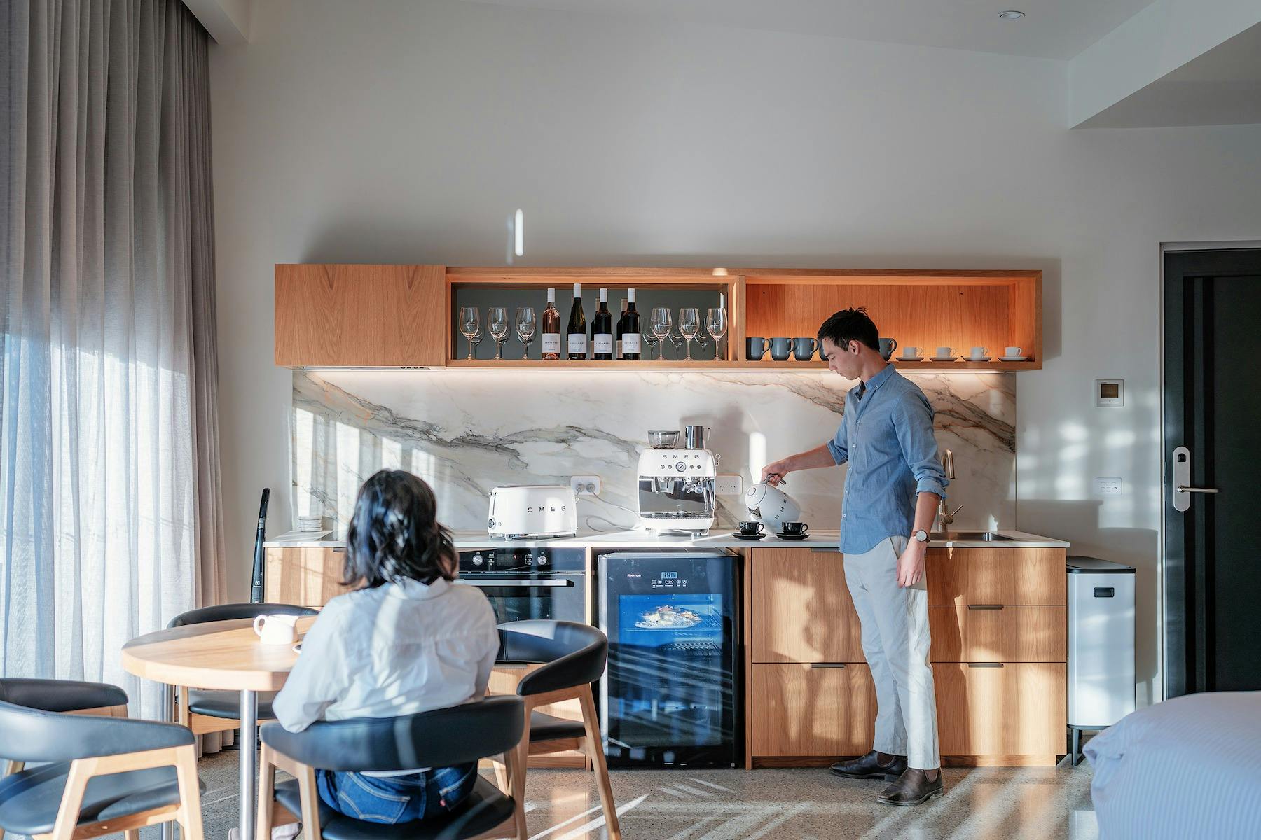 Woman seated at the table and man pouring water in cups