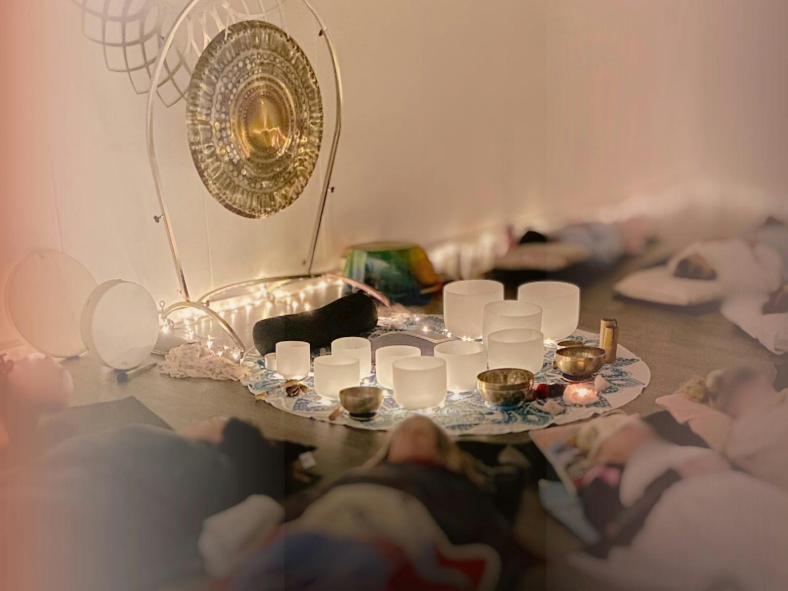 People resting on floor with sound bath set up (singing bowls & gong).