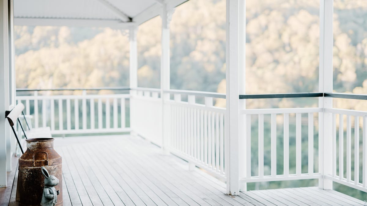 Photo of a wrap around verandah, featuring a rustic milk can and spectacular mountain views