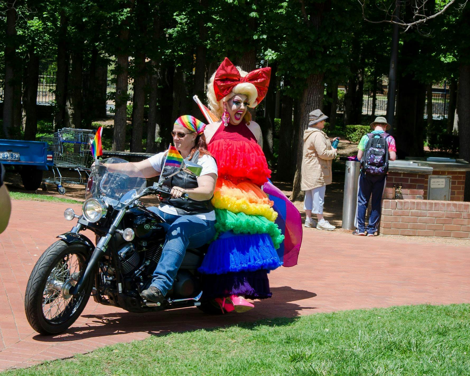 motorbike ridden by woman and drag queen passenger