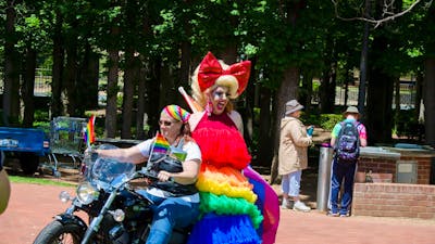motorbike ridden by woman and drag queen passenger