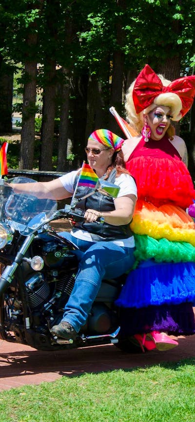 motorbike ridden by woman and drag queen passenger