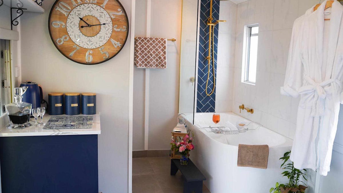 Stylish train carriage bath with gold fixtures, deep tub, and cozy decor for a relaxing escape.