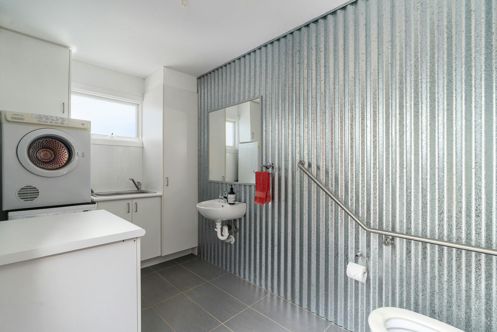 Laundry with washing machine, dryer, sink and spare toilet.