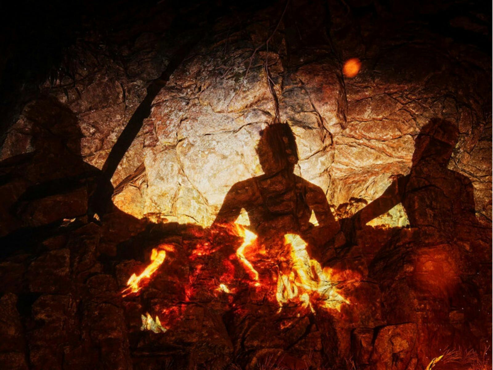 Shadows of figures cast against a rocky wall, illuminated by the warm, flickering light of a campfir