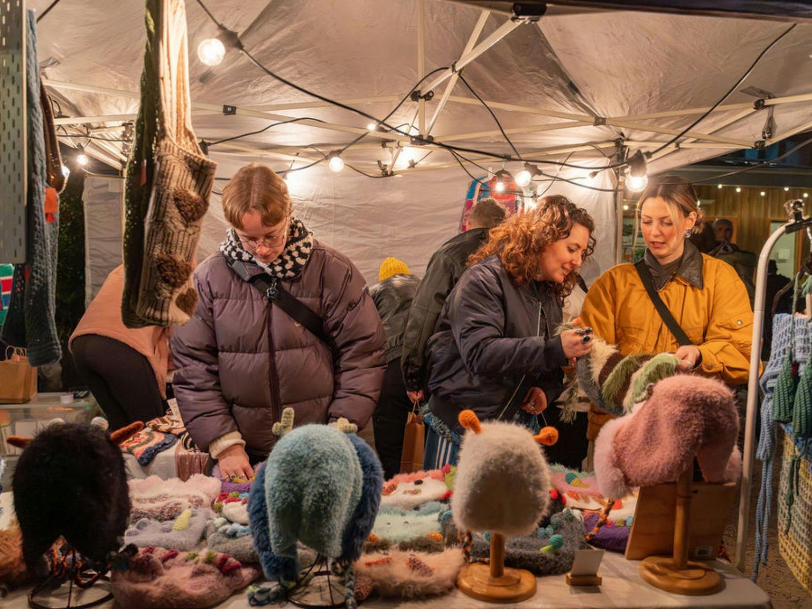 People shop in a stall selling knitted items