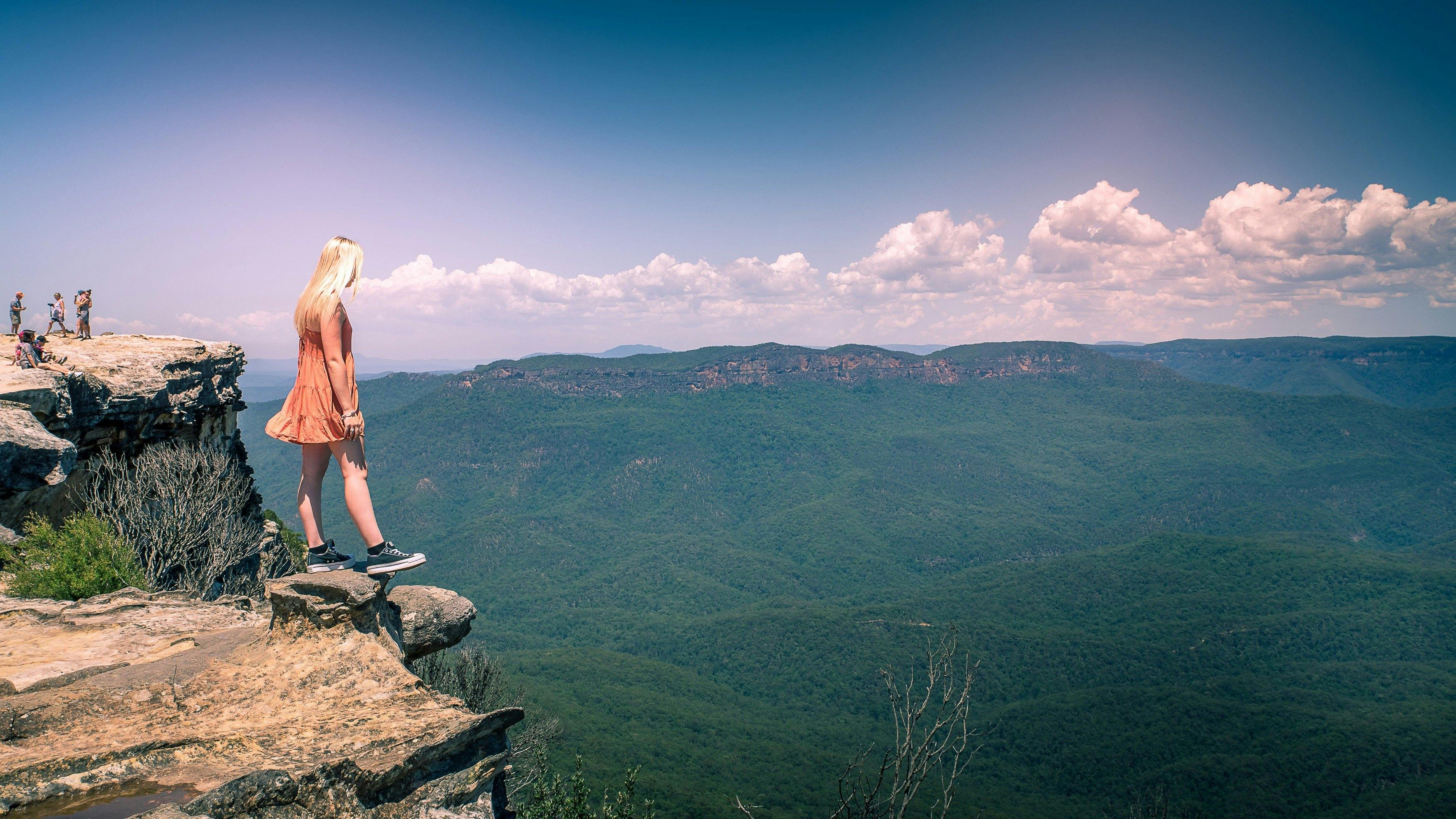 Girl standing on rock cliff edge overlooking valley