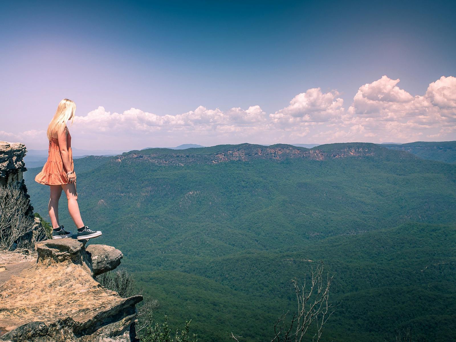 Girl standing on rock cliff edge overlooking valley