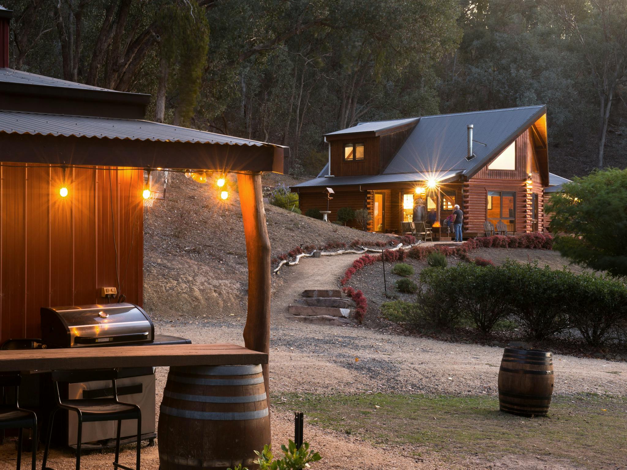Outdoor barbecue area with festoon lights and firewood barrel