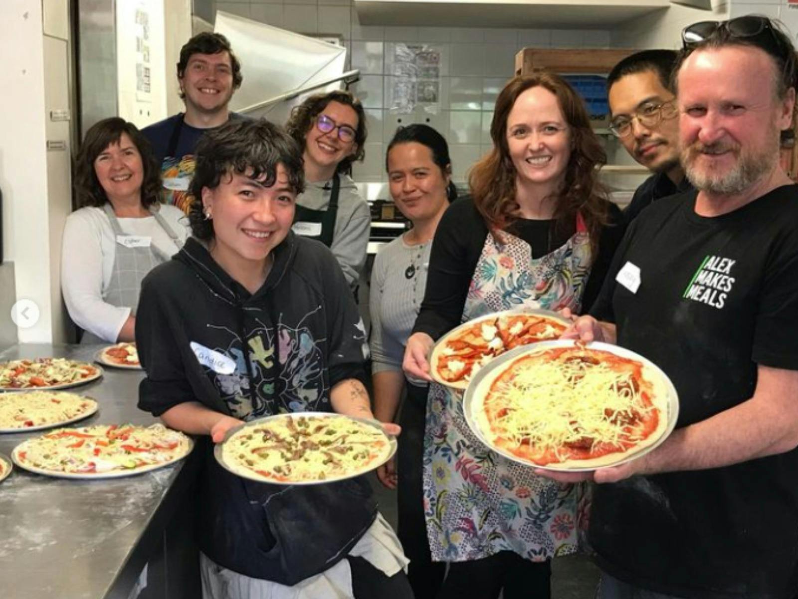 A group stand showing off their pizzas