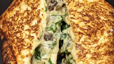 Toasted sandwich cut in half with filling oozing out