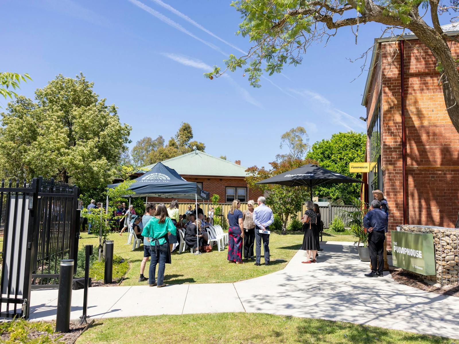 crowd gathered outside an old brick building at The Pumphouse Albury, sunny sky and picnic umbrellas