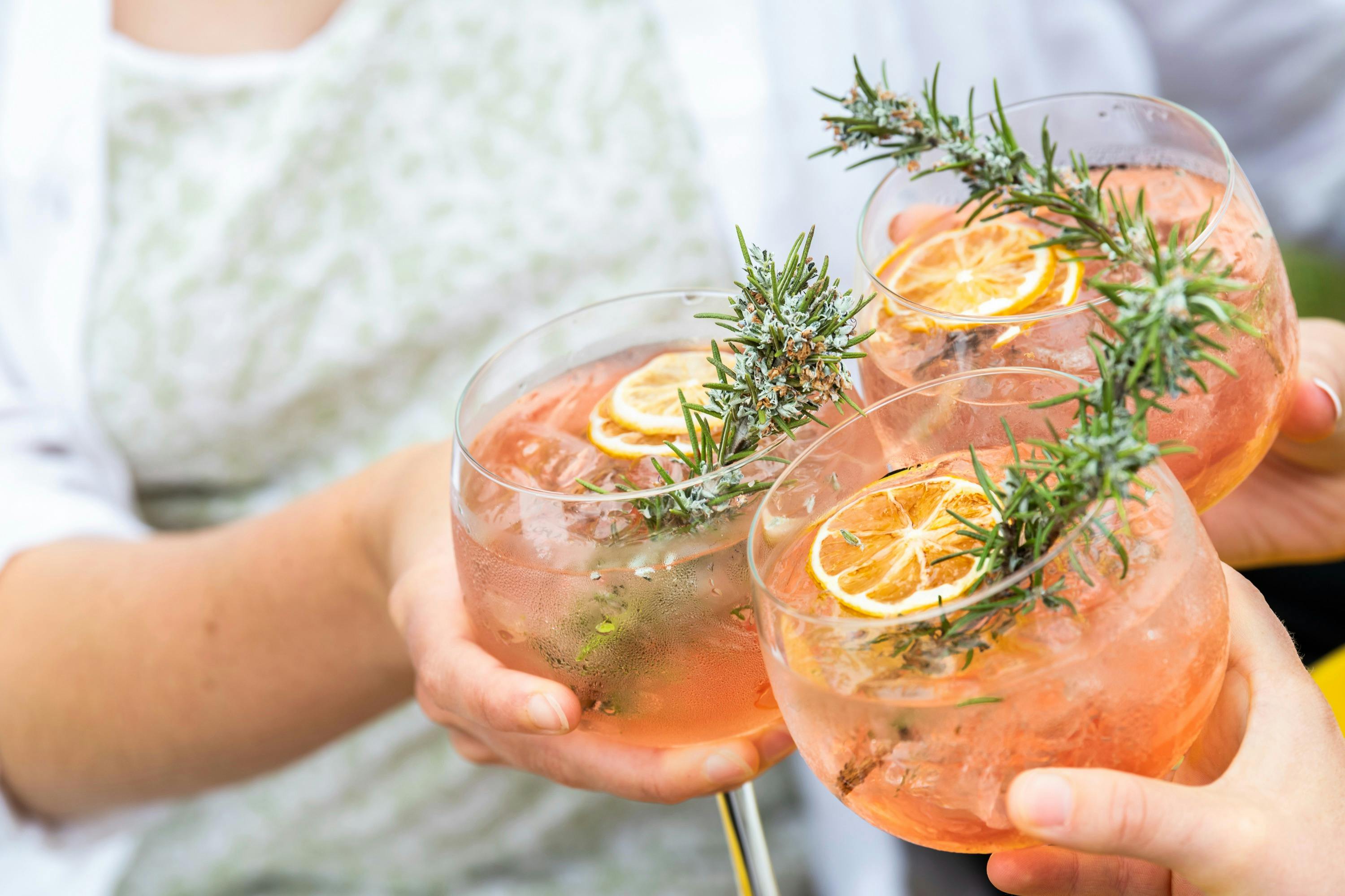 Three gin and tonics clink together to cheers