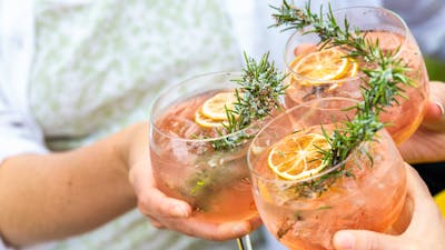 Three gin and tonics clink together to cheers