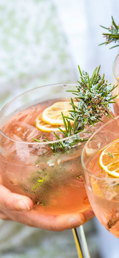 Three gin and tonics clink together to cheers