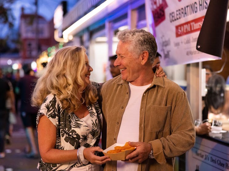 Couple enjoying takeaway food and drink in Little India in Harris Park