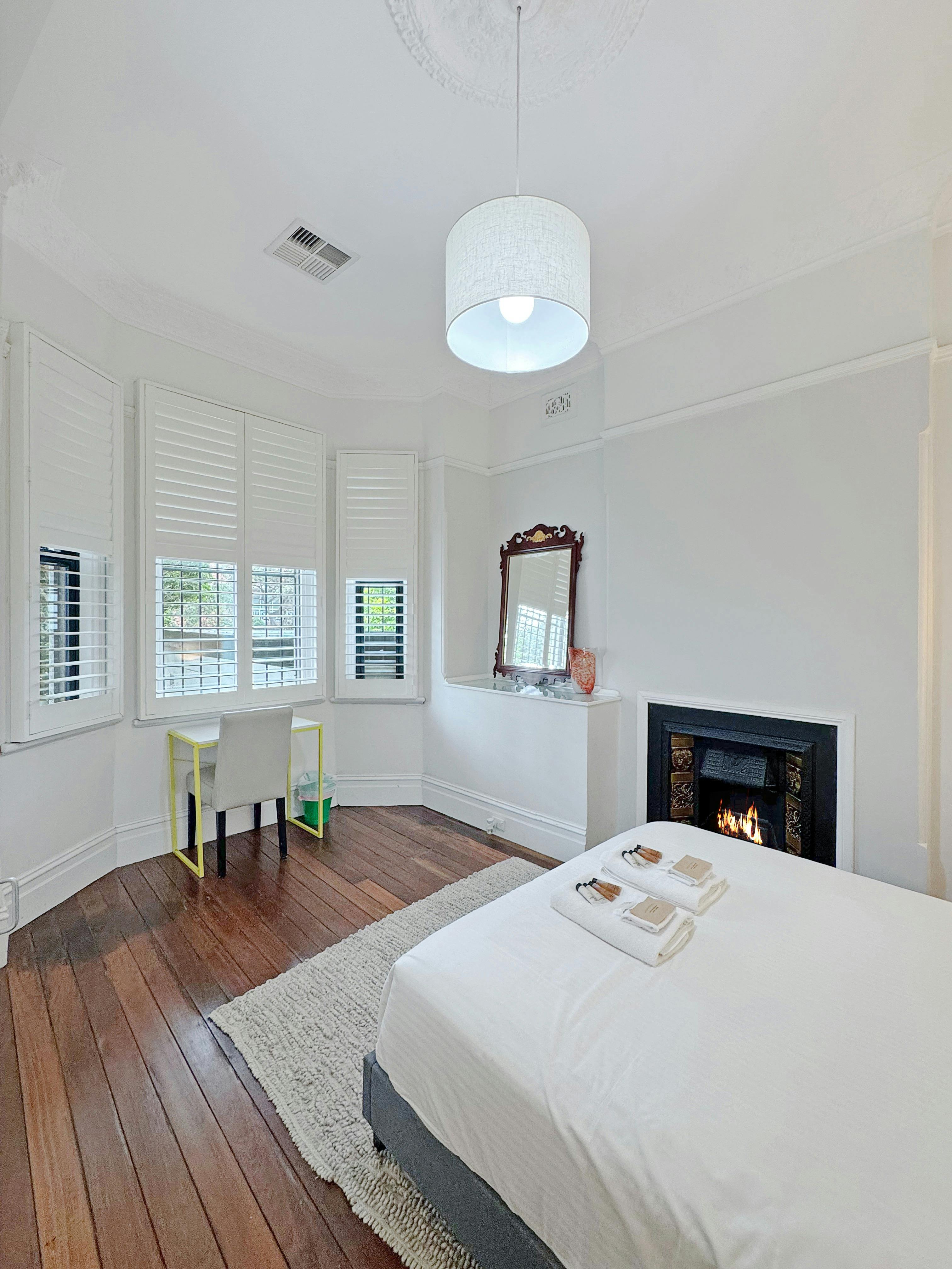 舒適的臥室，配有壁爐、書桌和漂亮的木地板。