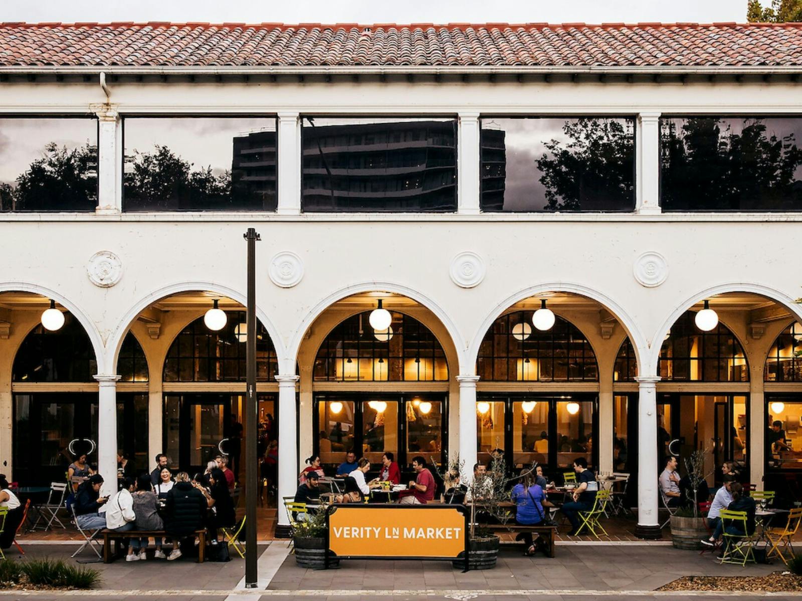 People sitting outside the building at bar tables in colonnade