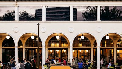 People sitting outside the building at bar tables in colonnade