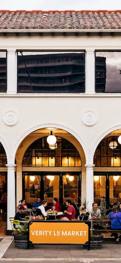 People sitting outside the building at bar tables in colonnade