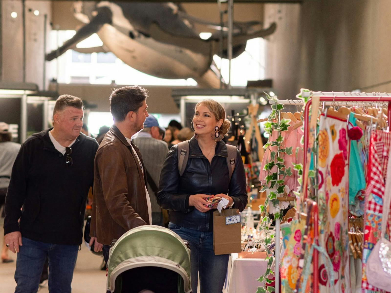 2 shoppers smiling at each other while standing in the market with the Museum Whales in the backgrou