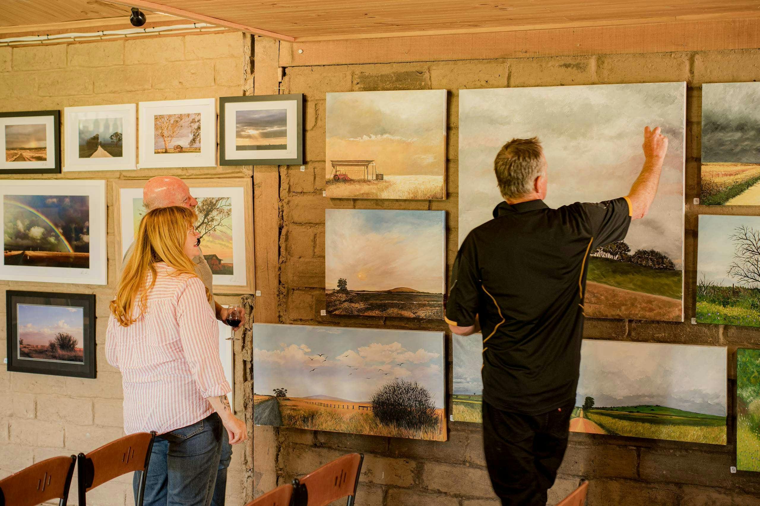 Paintings on show with people looking at them