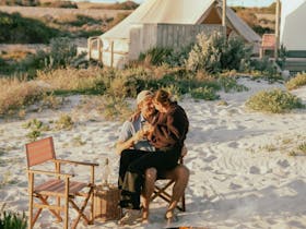 Couple relaxing beside the fire pit with the luxury bell tent in the background Salty Sands Retreats
