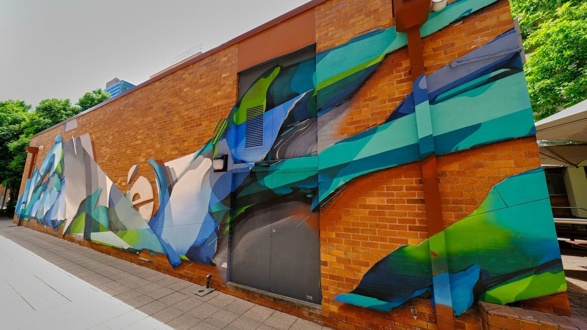 Blue and green street art piece on red brick wall