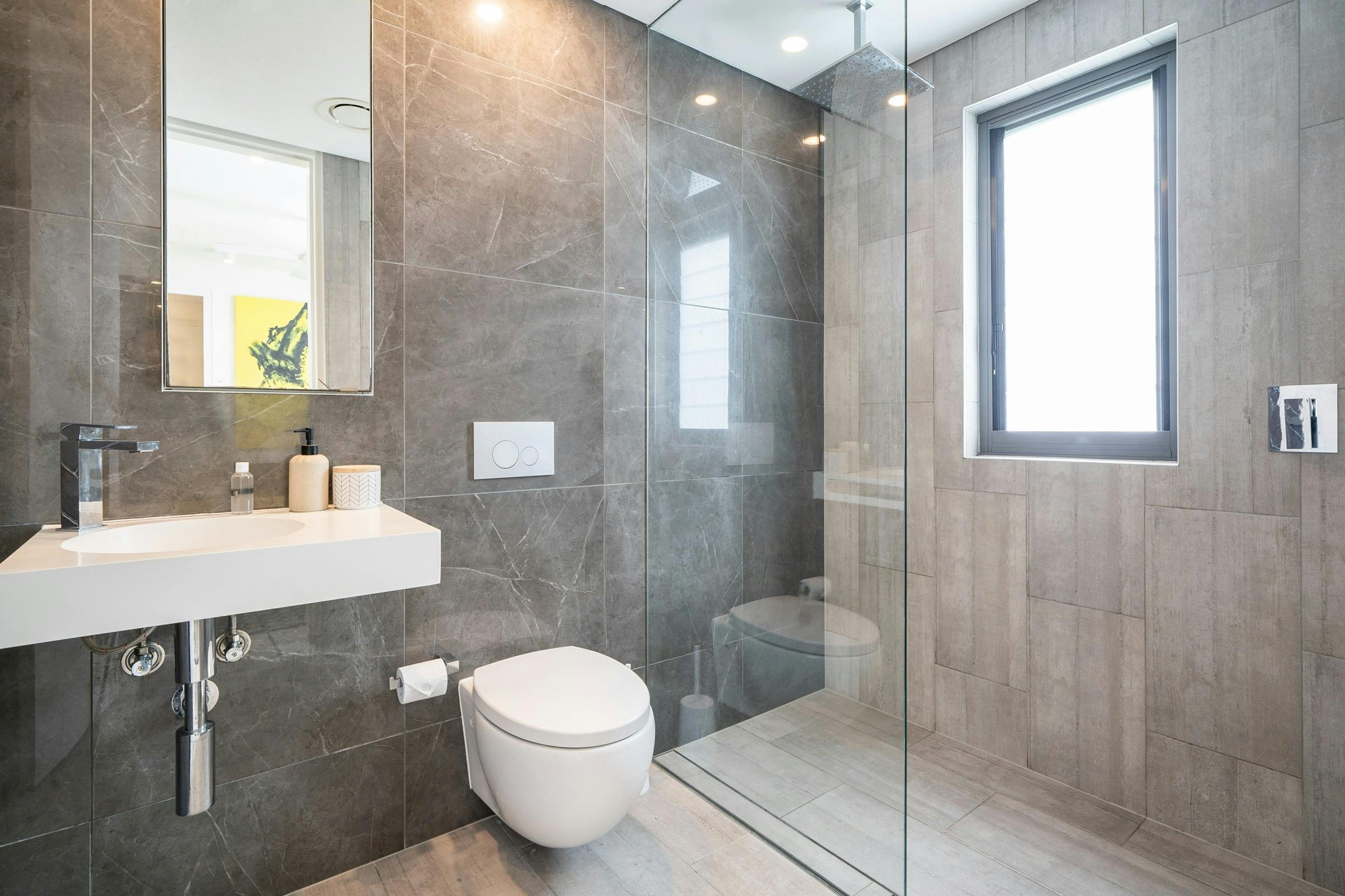 Sleek bathroom with glass shower, and a well-equipped laundry area with washing machine.