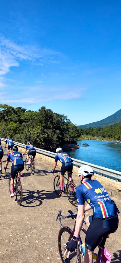 Cycle peloton crossing bridge in formation taken from behind cyclists, scenic