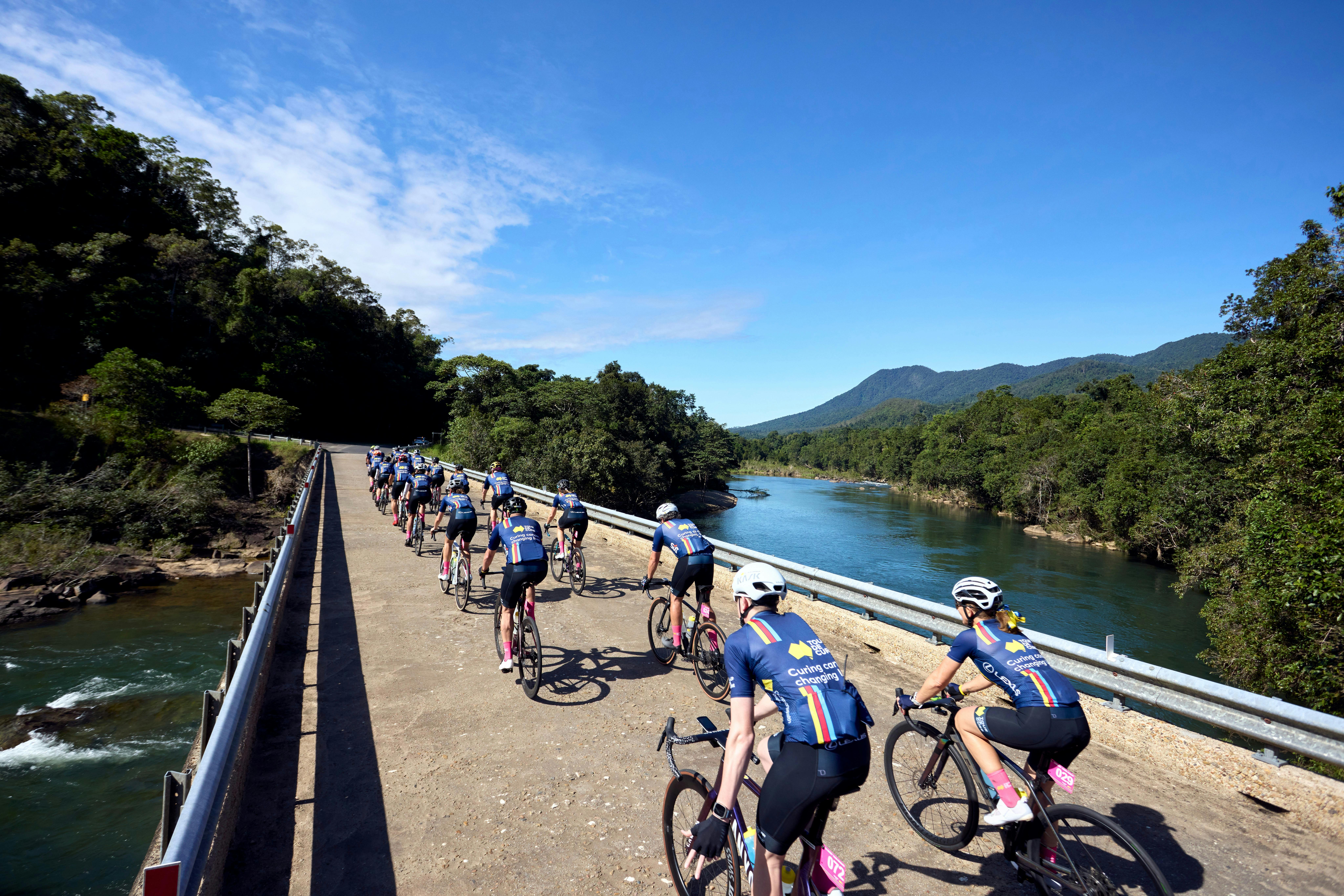 Cycle peloton crossing bridge in formation taken from behind cyclists, scenic