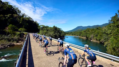 Cycle peloton crossing bridge in formation taken from behind cyclists, scenic