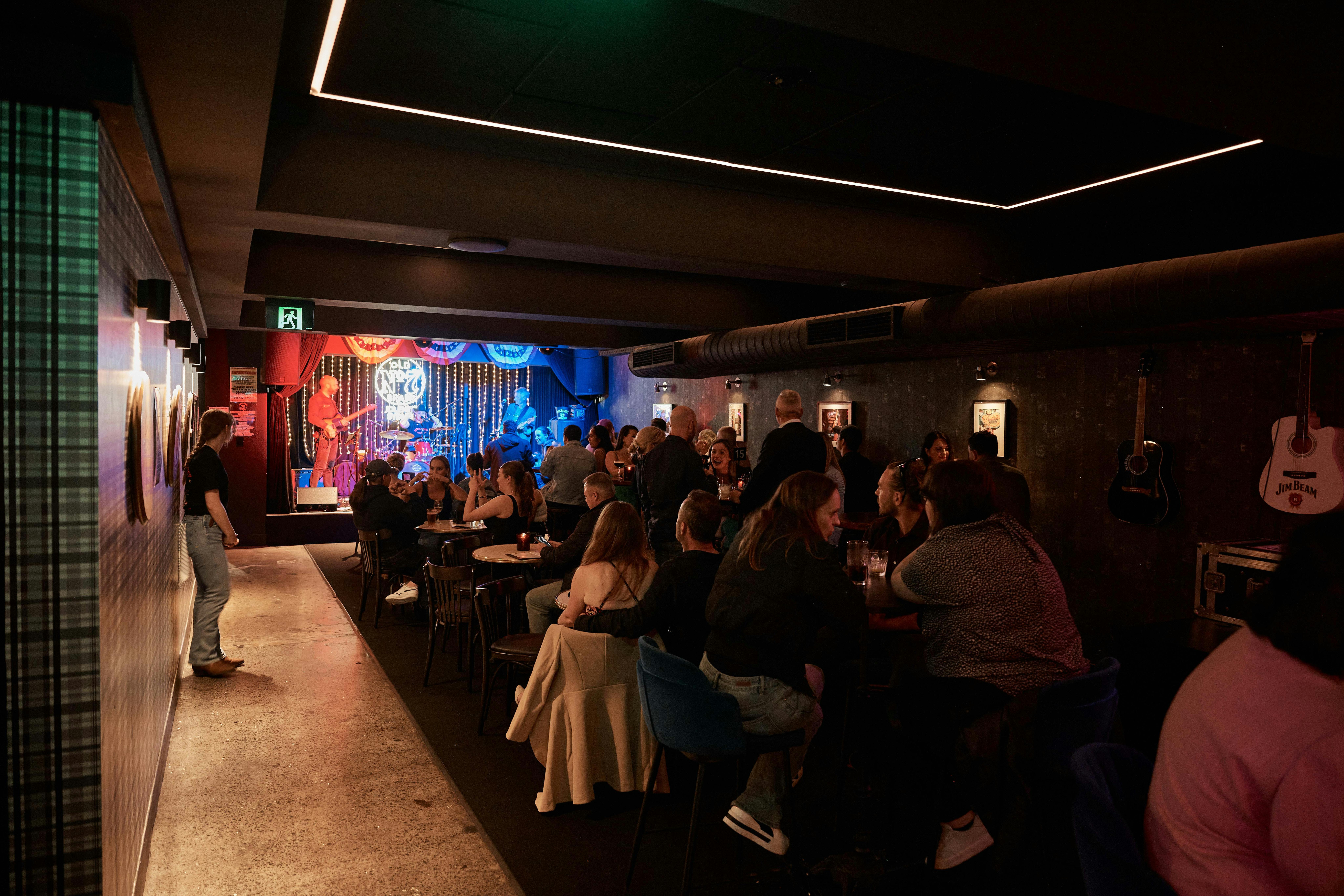 A busy bar with a stage in the background, with everyone watching the stage