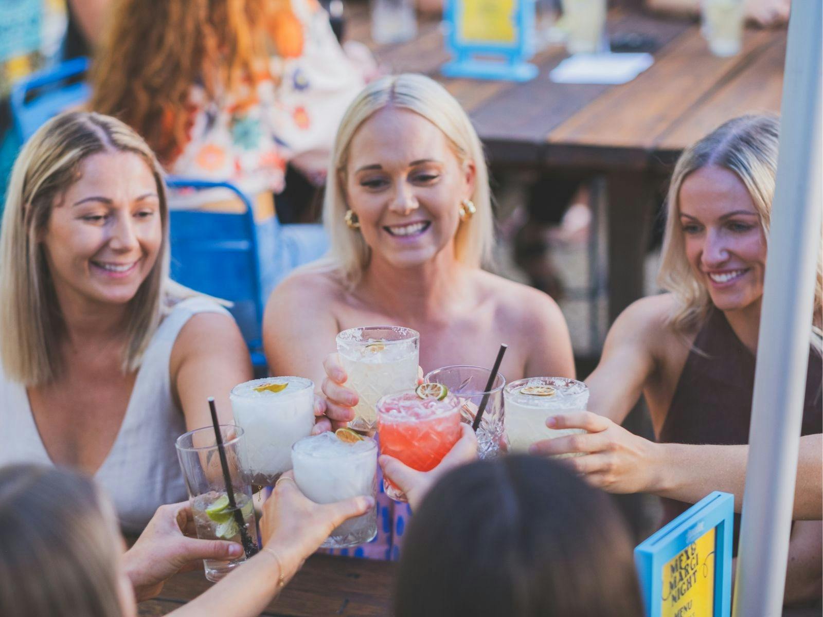 カクテルを持った女性グループが「乾杯！」と言っている。