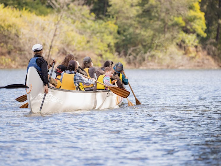 a large canoe with 14 people paddling away