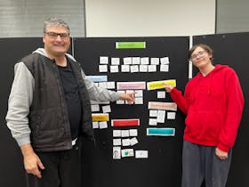 Picture of two men pointing to the middle board of information on emergency services