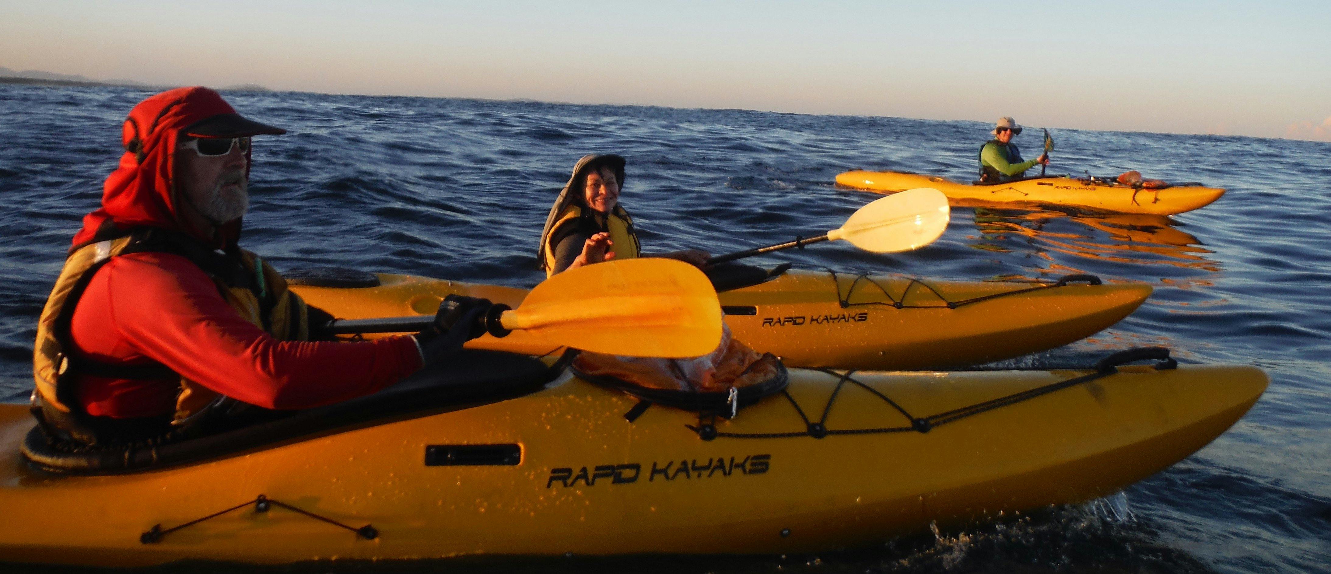 Kayak Port Stephens Broughton Island 투어에서 세 사람이 바다에서 카약을 노로 젓고 있습니다.