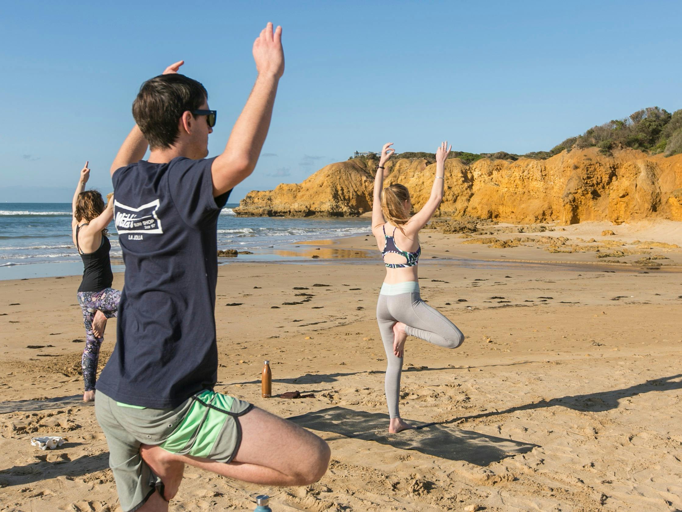 People doing yoga on a surf beach at Honu Honi Surf Camp.