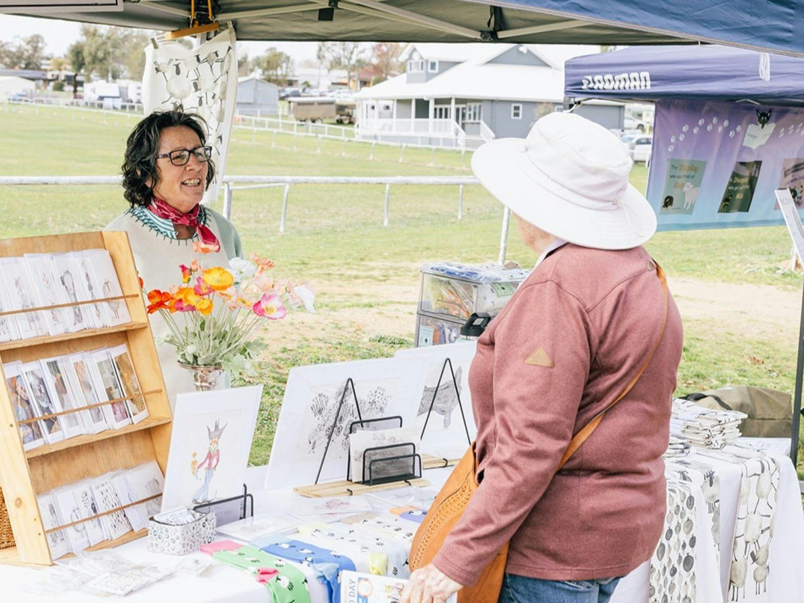 Stallholder selling woollen goods chatting to a customer.