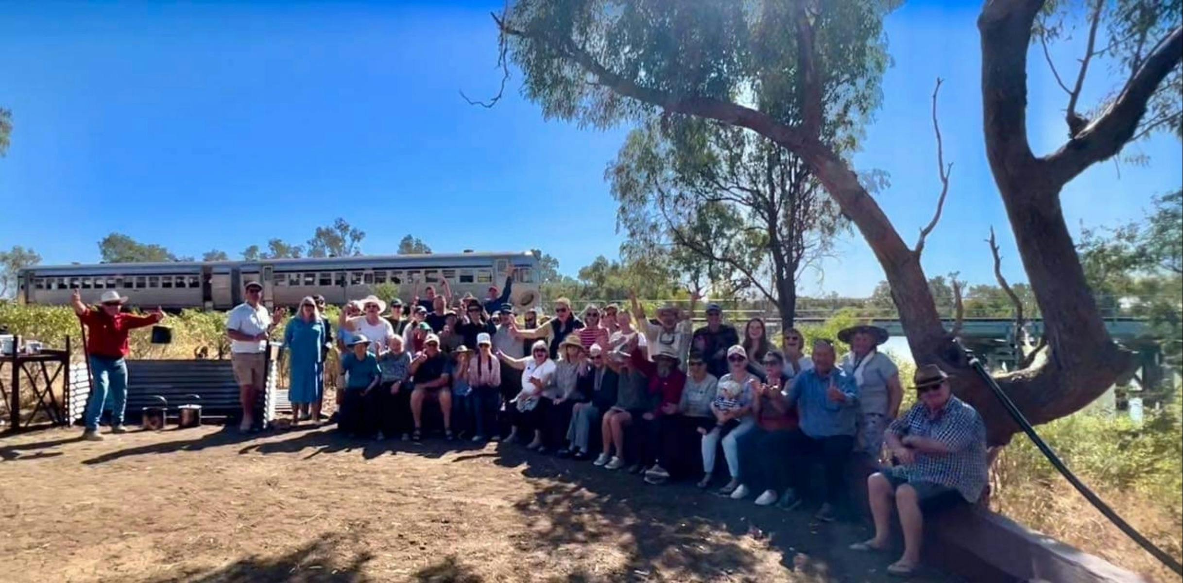 group of guests on the riverbank with train in the distance