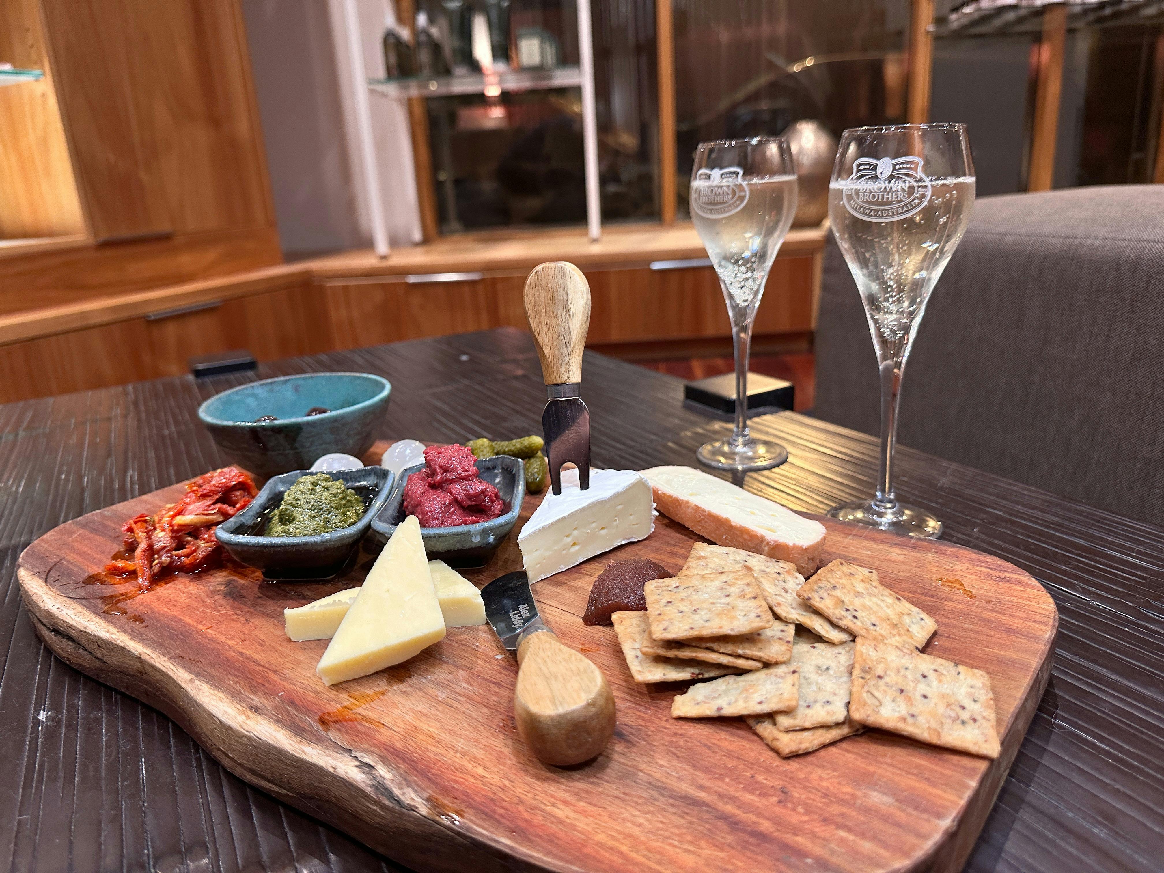 Cheeseboard with crackers, cheese, dips and forks in the cheese, with two glasses of champagne