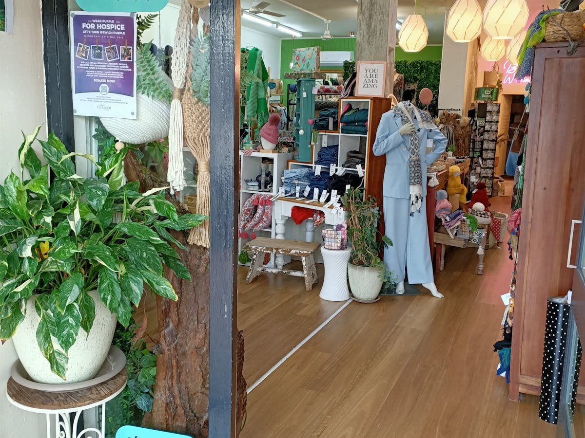 Picture taken looking through the front door at a display mannequin surrounded by greenery.