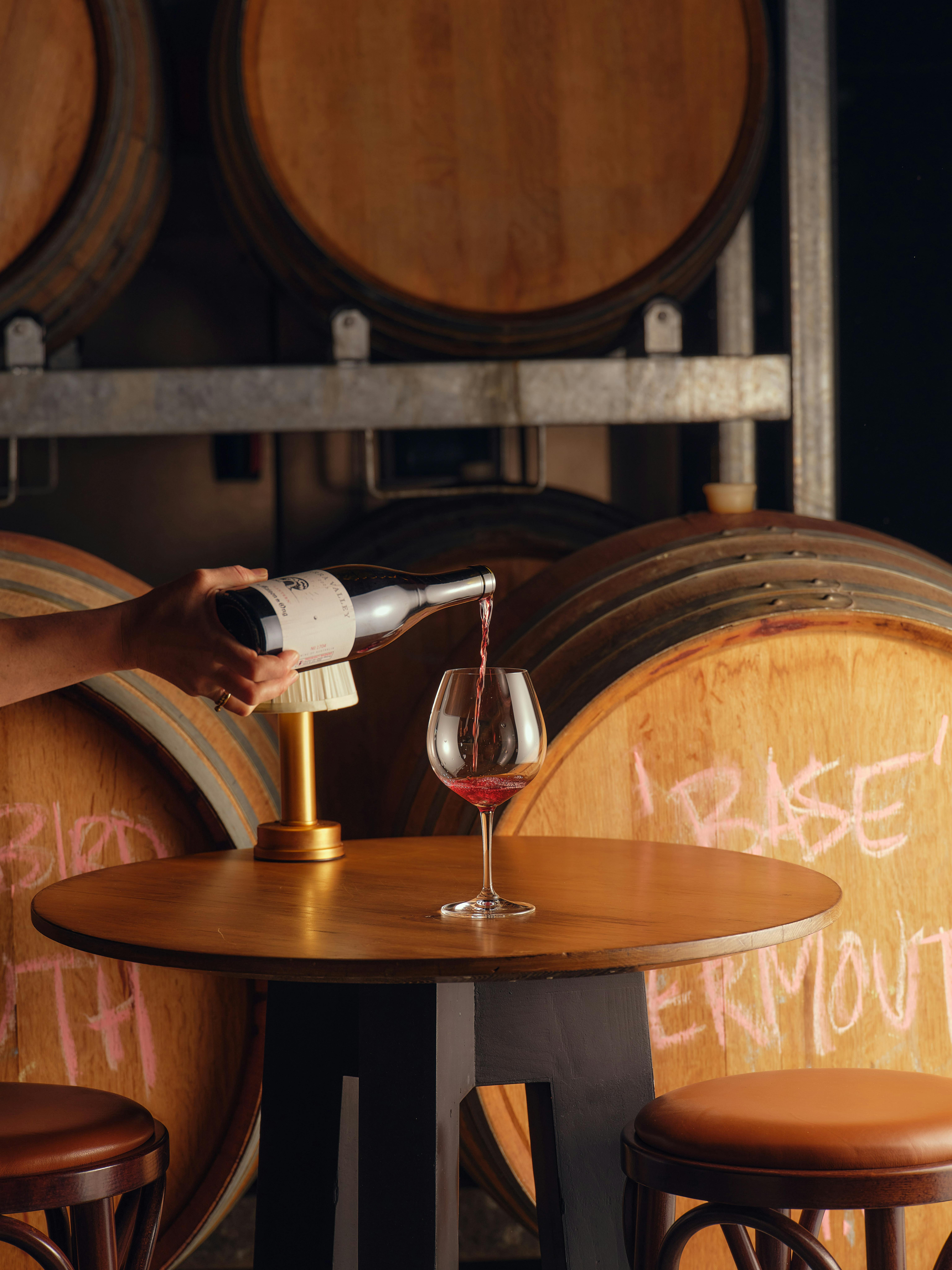 Glass of red wine being poured into a large pinot glass