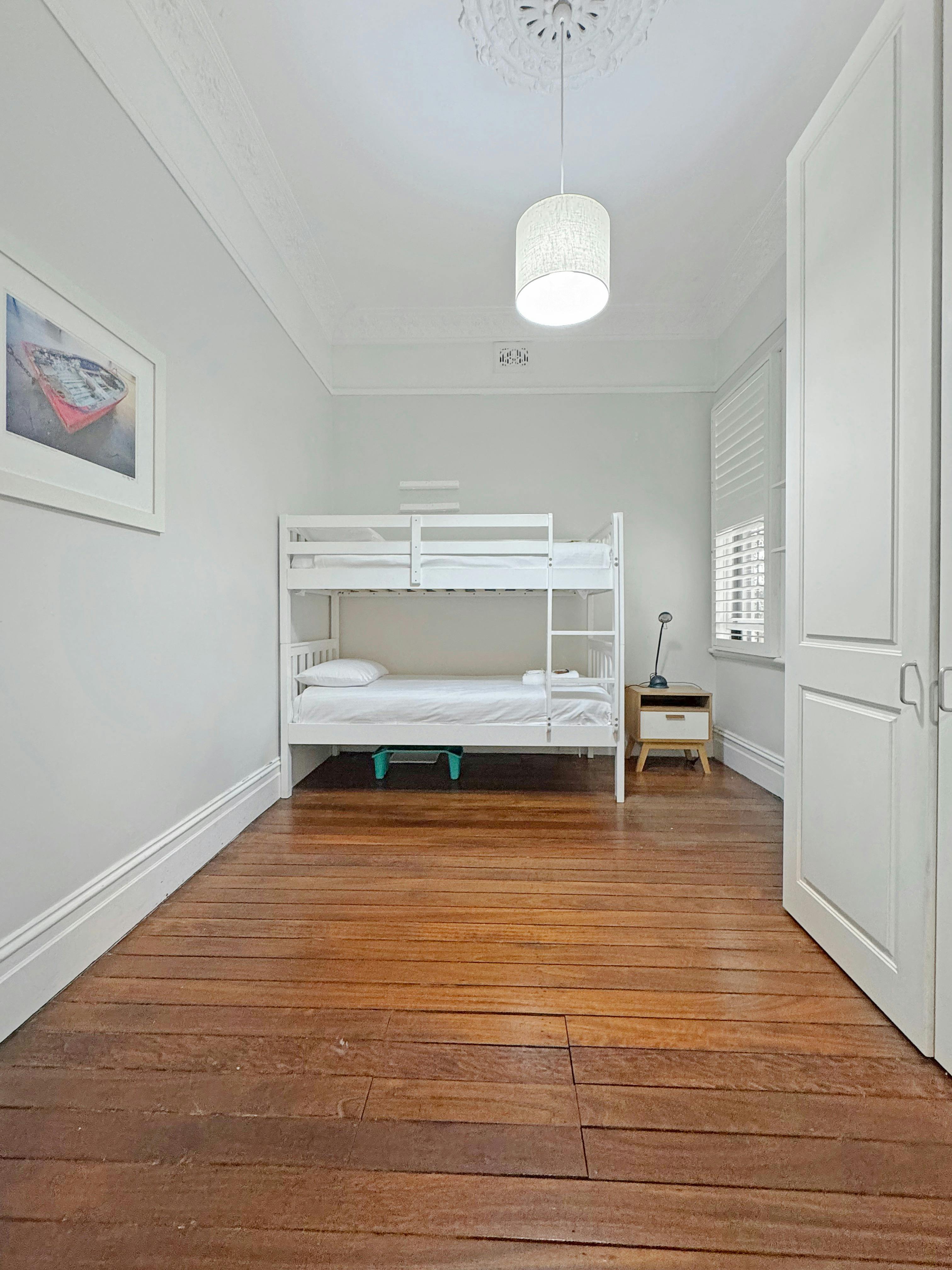 兒童房配有雙層床、明亮的牆壁和木地板。