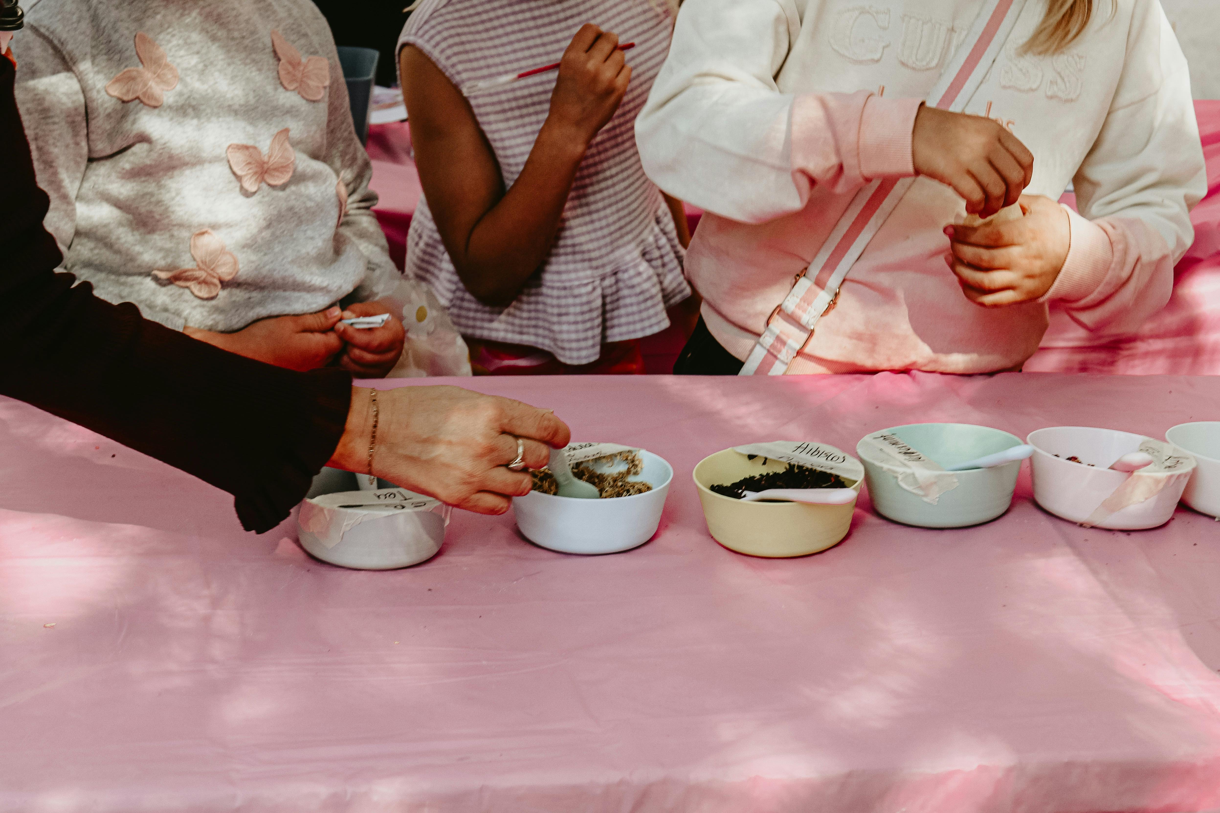 An image of potion ingredients on a table, with kids hands taking the ingredients.