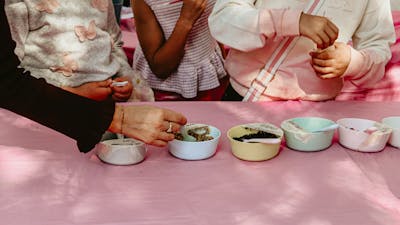 An image of potion ingredients on a table, with kids hands taking the ingredients.