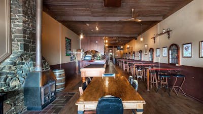 Pot belly woodfire on left-hand wall surrounded by stonework, with seating area and pool table throu