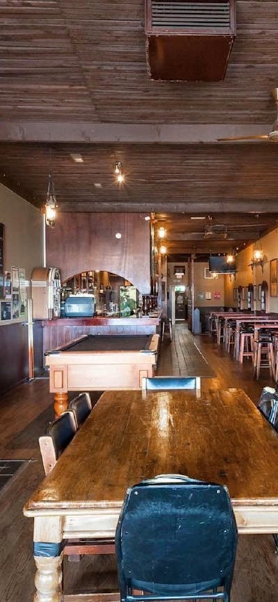 Pot belly woodfire on left-hand wall surrounded by stonework, with seating area and pool table throu